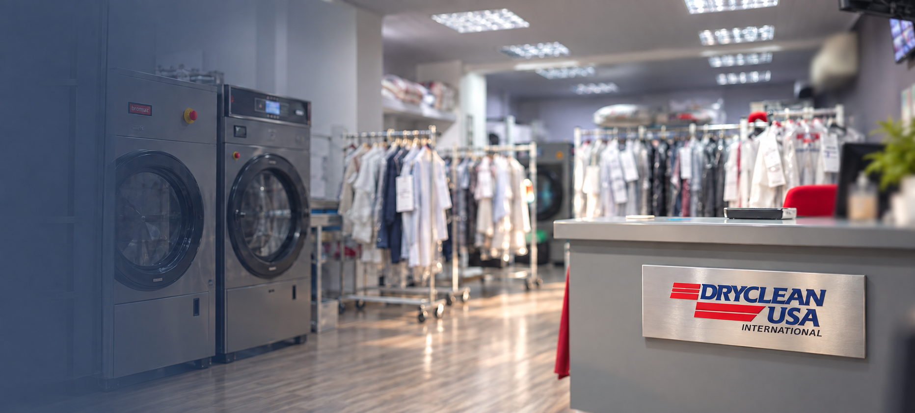Salão amplo de uma unidade DryClean USA, com máquinas profissionais, araras de roupas e o logotipo da marca aplicado no balcão